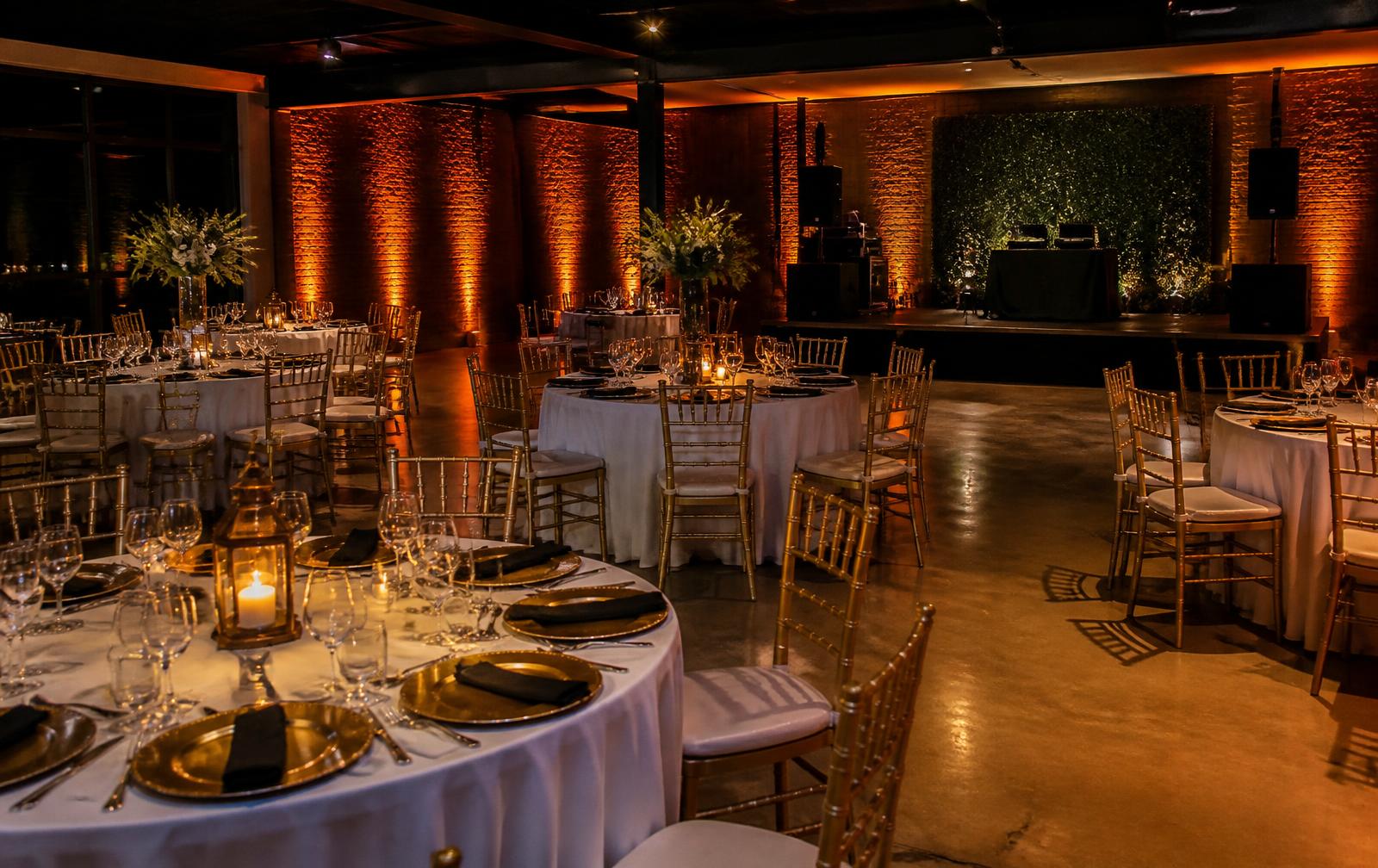 Event hall set with round tables, gold chairs and amber uplighting
